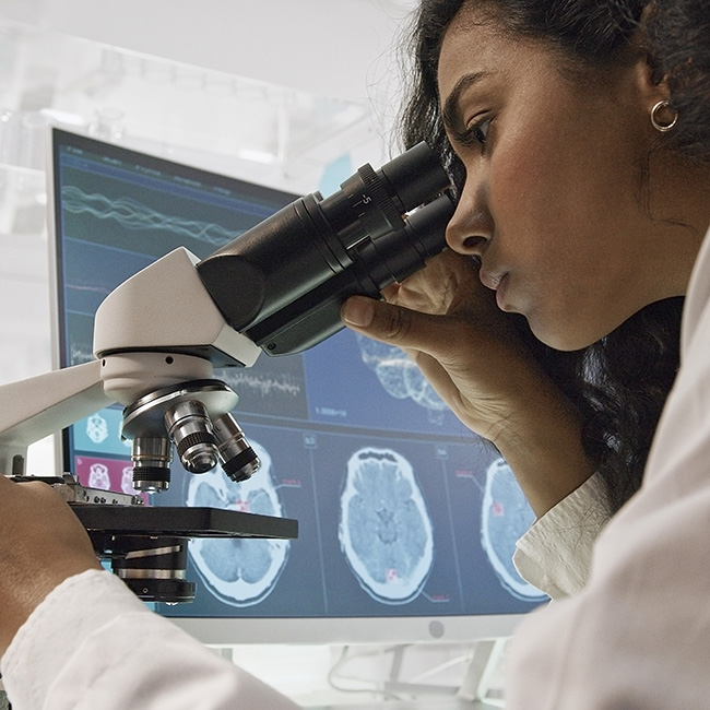 Asian ethnicity woman using microscope. Brain tissue donation helps advance research.