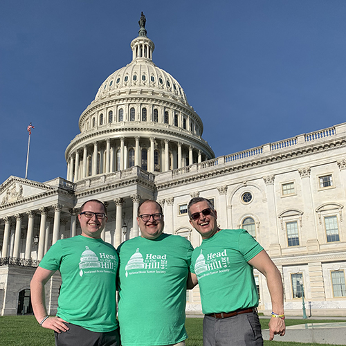 Three men in green Head to the Hill t-shirts stand in front of the U.S. Capitol.