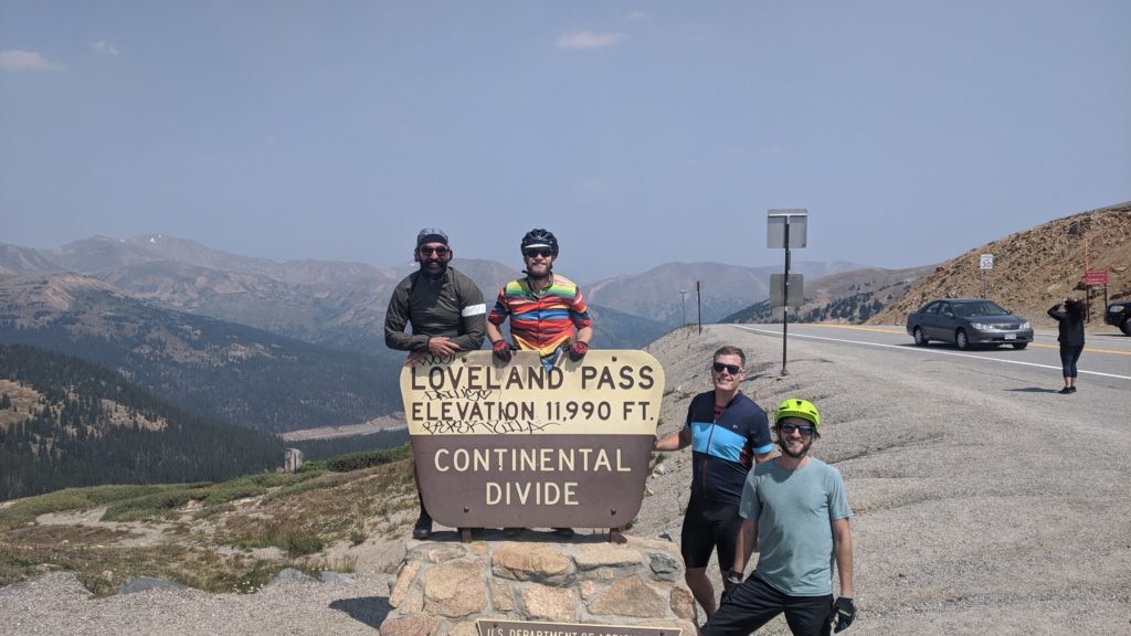 Four cyclists gather at an elevation marker during their Colorado ride.