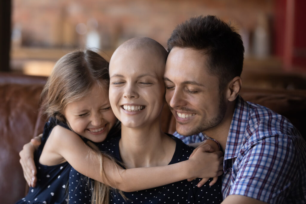 Happy daughter kid and dad hugging ill hairless mom, fighting against cancer. 