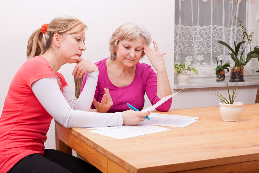 Two women pondering in living room over advance care planning documents