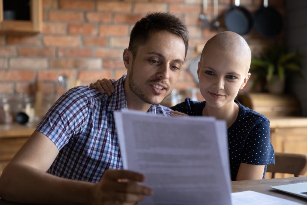 Female cancer patient sits next to male companion and looks at health care proxy form.