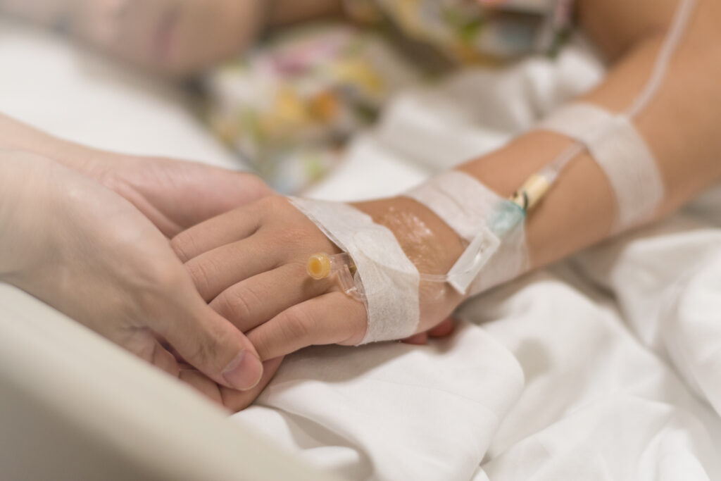 A brain tumor patient holds hands with a loved one following a craniotomy.