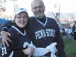 Decked out in Penn State gear, Bridget and Rich hug on the university campus.