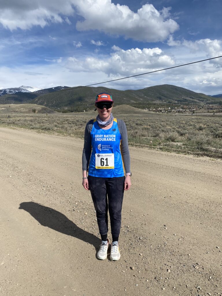 A woman in a hat wearing a Gray Nation Endurance bib stands on a dirt road in California. 