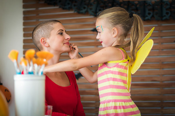 Cute little girl applying face paint to her mother's face.