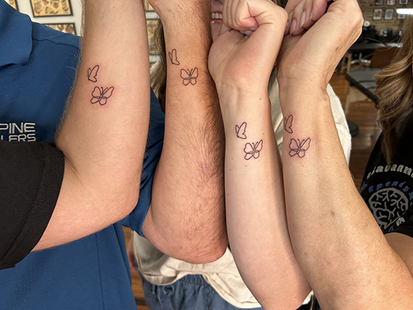 A family shows their four matching butterfly tattoos on their forearms after Savannah's ependymoma diagnosis.