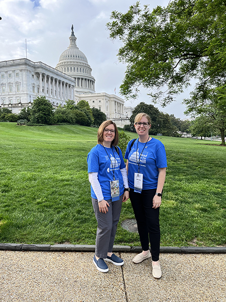 Two women stand in front of the U.S. Capitol wearing 2024 Head to the Hill t-shirts.