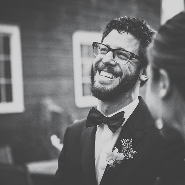 A man in a tux smiles wide.