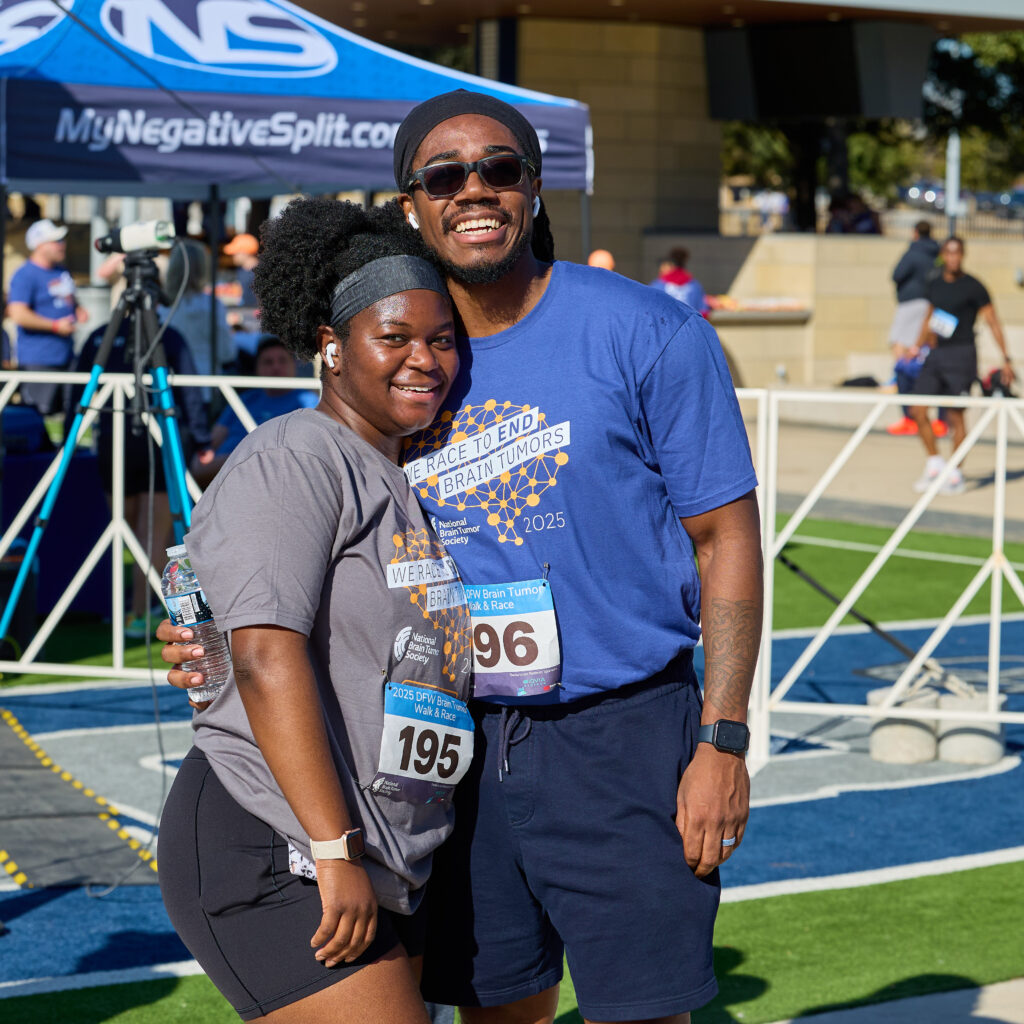 A man wraps his arm around his wife wearing a survivor t-shirt at the DFW Brain Tumor Walk & Race. Less than a year after being diagnosed with prolactinoma, she won the female survivor category.