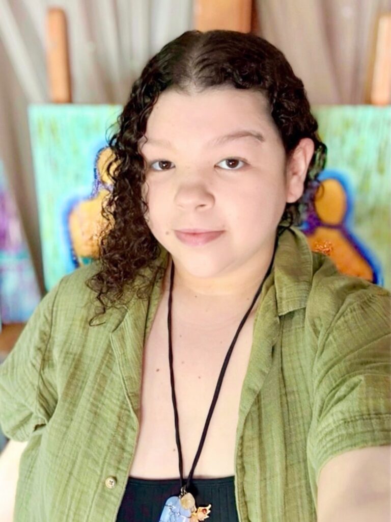 A woman in a green shirt looks at the camera with abstract art behind her.