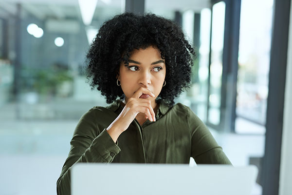 Shot of a young businesswoman, who is returning to work after a brain tumor diagnosis, looking thoughtful while using a laptop in a modern office.