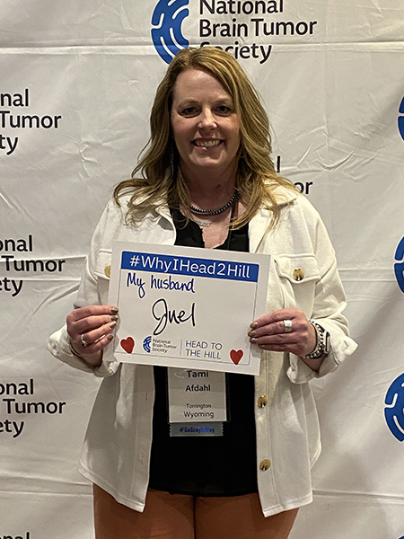 A woman, who advocates for the BRAIN Act, holds up a sign that reads, "#WhyIHead2Hill - My husband Juel"