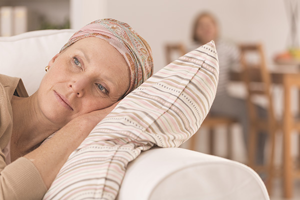 Tired woman after brain tumor radiation treatment lying on couch at home. Prioritizing rest is important in managing side effects.