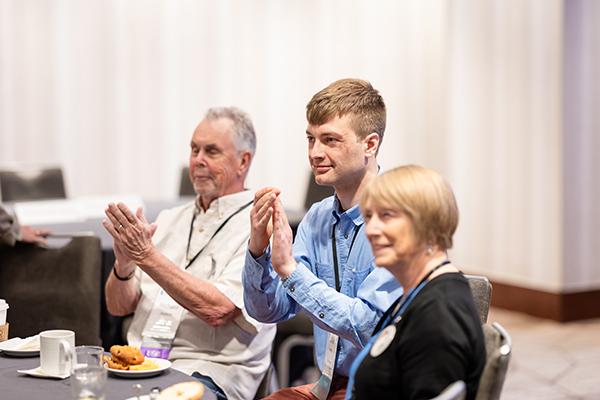 A few brain tumor research advocates listen and clap at an event.