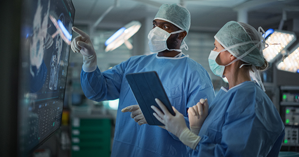 Diverse colleagues — one male and one female — having a discussion In the operating room while looking at imaging.