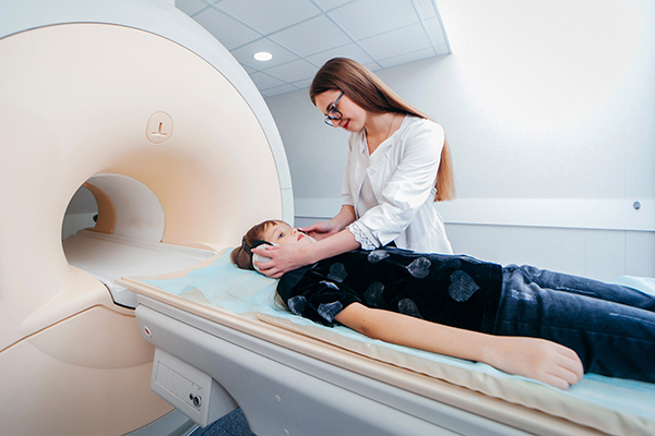 Female tech and boy with medulloblastoma prepping for an MRI.