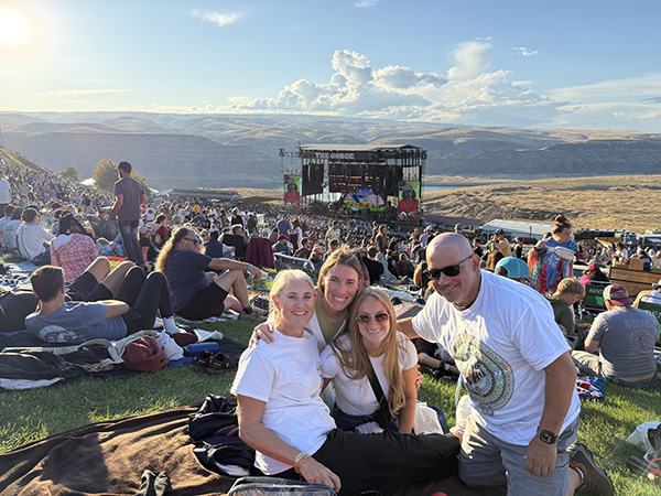 Two parents and their young adult daughters pose for a photo atop a hill at a concert at The Gorge.